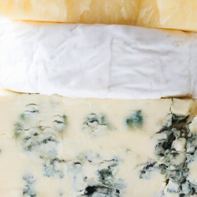 Close-up of assorted cheeses stacked with distinct textures. Ideal for gourmet food inspiration.